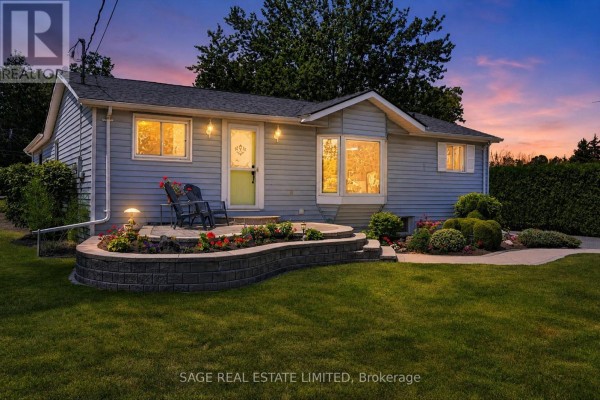Front exterior of a light blue bungalow with a green door and a paved walkway. - 39 Riverside Drive, Kawartha Lakes