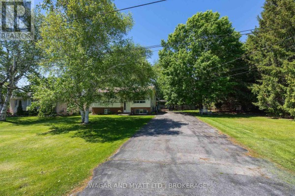 Wooden deck with barbecue and sliding glass doors overlooking a treed backyard. - 39 Riverview Drive, Greater Napanee