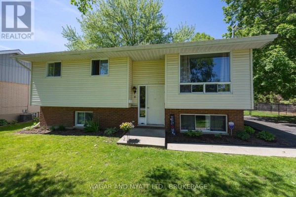 Entrance hall with white door, hardwood floor, and staircase with metal railing. - 39 Riverview Drive, Greater Napanee