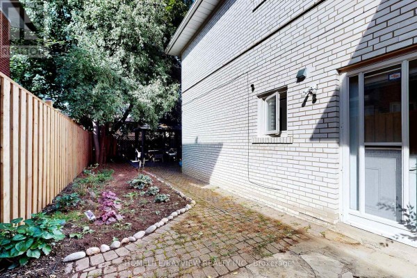Side exterior of house with brick siding, paved walkway, and backyard garden. - 39 Shenstone(basement) Road, Toronto