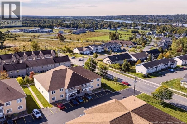 Aerial view of the apartment complex surrounded by suburban homes and distant city skyline. - 39 Sunny Brae Drive Unit# 214, Fredericton