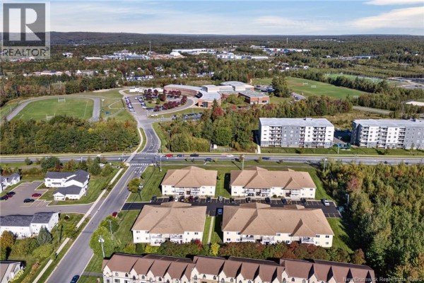 Aerial perspective showcasing the apartment buildings within a larger neighborhood with a school and park. - 39 Sunny Brae Drive Unit# 214, Fredericton