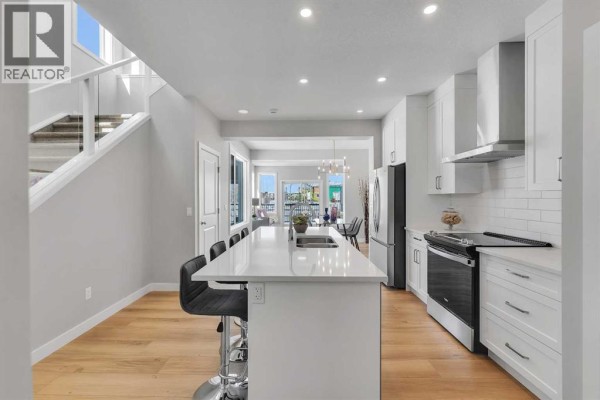 Wooden deck with black railing overlooking a snow-covered yard and playground. - 390 South Shore Drive, Chestermere