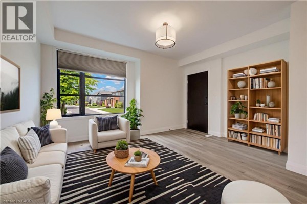 Living room featuring a large window, neutral furniture, and a wooden bookshelf. - 3900 Savoy Street Unit# 15, London