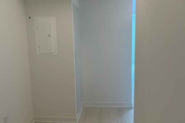 Interior hallway with white walls, light wood floors, and a utility panel. - 3902 - 3900 Confederation Parkway, Mississauga