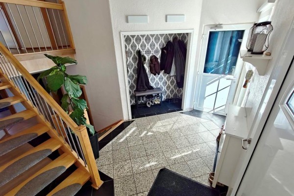 Interior foyer with a tiled floor, a wooden staircase with metal railings, and a coat rack by the door. - 39044 Road 34n Road, La Broquerie