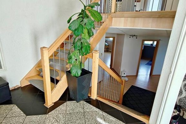 View of a light wood staircase with metal spindles in the center of the home's foyer. - 39044 Road 34n Road, La Broquerie