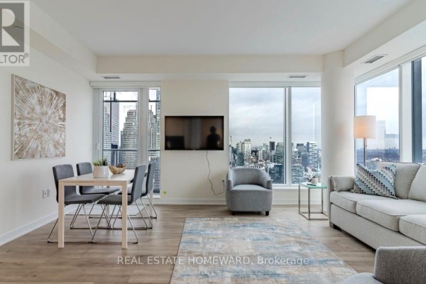 Living room and dining area with seating, television, windows, and city view. - 3907 - 28 Freeland St. Street, Toronto