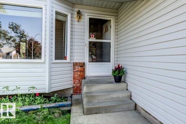 Concrete front steps lead to a white front door with a screen door. - 3908 28 Av Nw, Edmonton