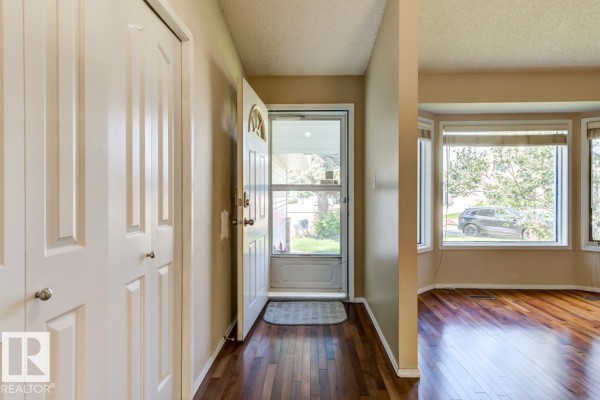 Interior view of a home entrance with a white door, double closet, and bay windows. - 3908 28 Av Nw, Edmonton