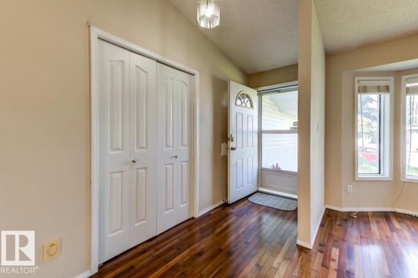 Interior view of a home entrance with a white door, double closet, and bay windows. - 3908 28 Av Nw, Edmonton