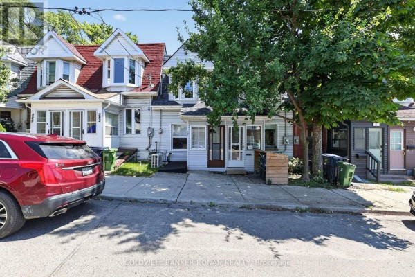 Exterior of white townhouse with red car parked on street. - 391 Jones Avenue, Toronto