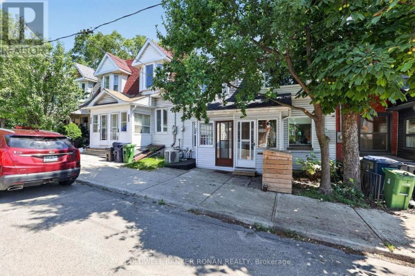 Street view of white townhouse with sidewalk and trees. - 391 Jones Avenue, Toronto