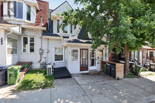Close-up exterior view of white townhouse entrance with trees. - 391 Jones Avenue, Toronto