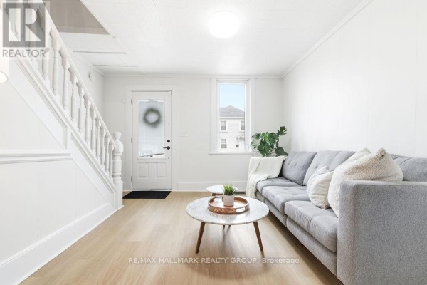 Living room view showing sofa, decorative table, and staircase leading to upper level. - 391 Murray Street, Pembroke