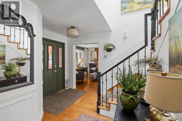 Foyer with dark green double doors, wood floors, white wainscoting, and staircase. - 3914 St. Clair Road, Stoney Point