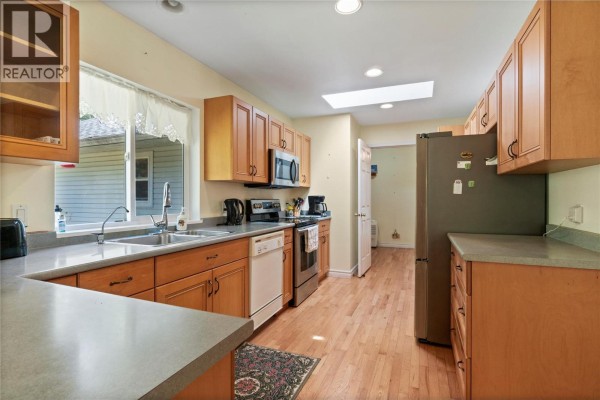 Kitchen with light wood cabinets, grey countertops, stainless steel appliances, and a skylight above. - 3915 Express Point Road, Scotch Creek