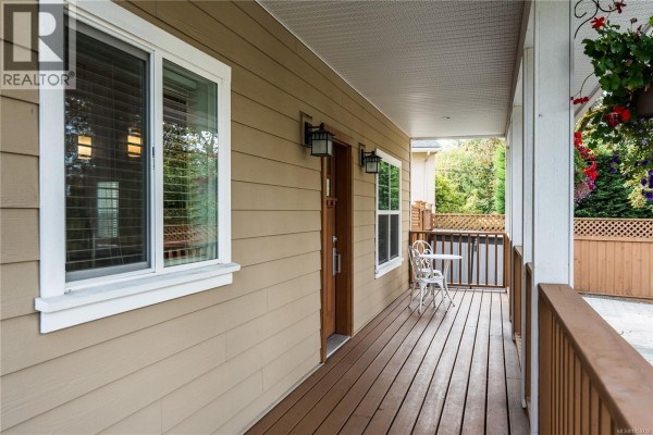 A covered porch with wooden decking and railings, a window, and a door. - 3919 Blenkinsop Rd, Saanich