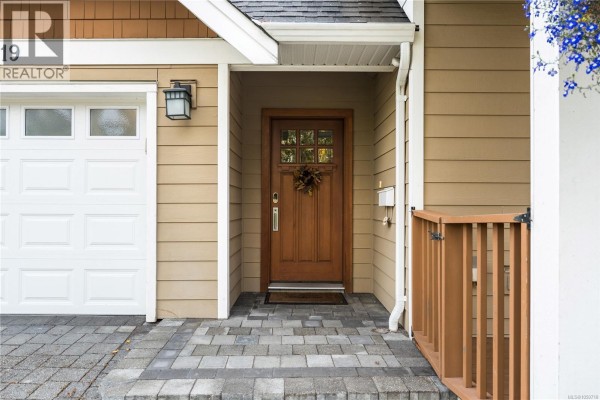 Close-up of the front door, white garage door, and paved walkway of the house. - 3919 Blenkinsop Rd, Saanich