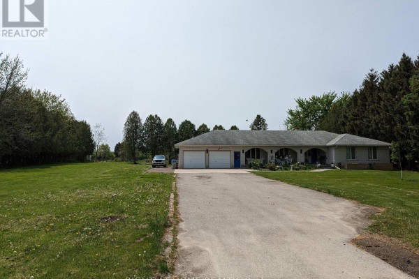 Driveway leading to a beige detached house with a three-car garage and a covered front porch. - 392 Second Street, Strathroy Caradoc