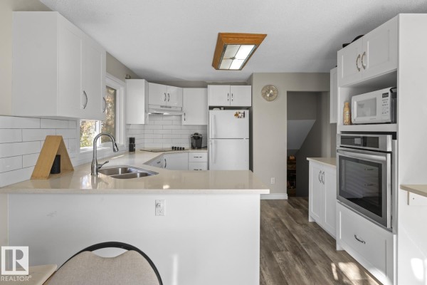 Kitchen with white cabinets, quartz countertops, stainless steel appliances, and a subway tile backsplash. - 3920 52 Av, Cold Lake