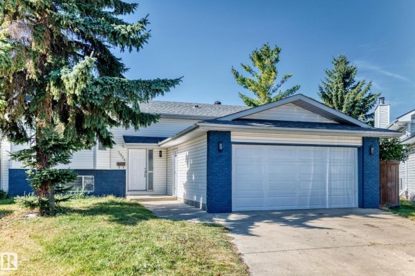 View of the house exterior with a driveway, lawn, and mature trees. - 3924 26a Av Nw, Edmonton