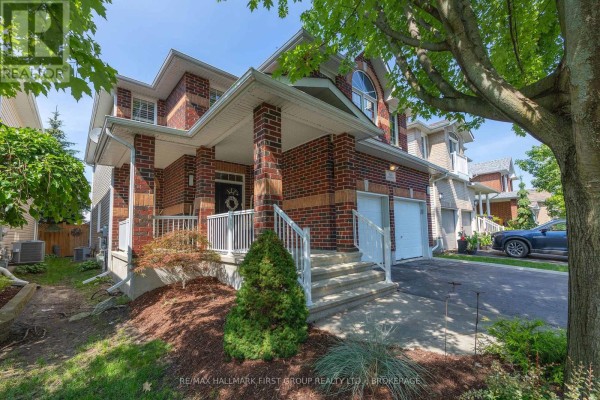 Side view of the front entrance and garage of a brick house with landscaping. - 393 Cavendish Crescent, Kingston