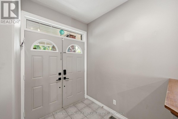 Interior view of a hallway showing double doors with arched windows and a tiled floor. - 393 Cavendish Crescent, Kingston