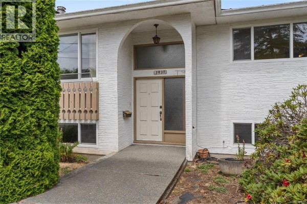 Front entrance of a white stucco house with a beige door and an arched entryway. - 3931 Braefoot Pl, Saanich