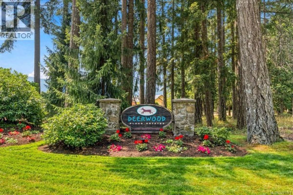 Entrance sign for Deerwood Place Estates with stone pillars and trees. - 3931 Excalibur St, Nanaimo