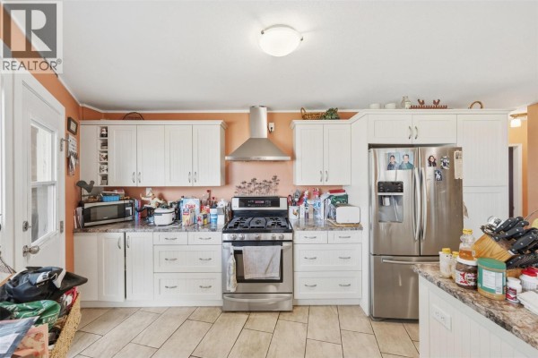 Kitchen with white cabinets, stainless steel appliances, and granite countertops. - 3935 Lakeside Road, Penticton