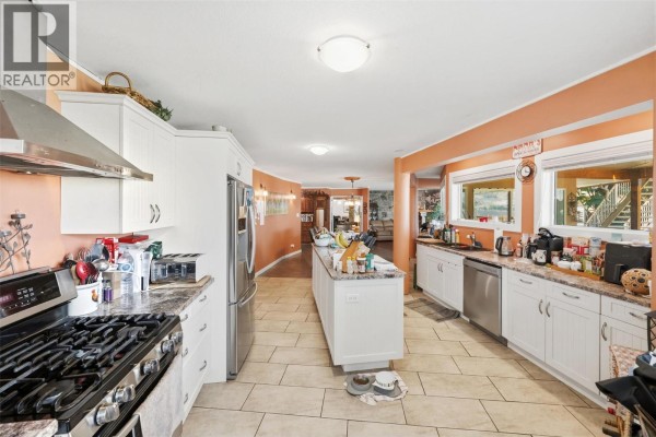 Spacious kitchen featuring an island, white cabinets, and orange accent walls. - 3935 Lakeside Road, Penticton