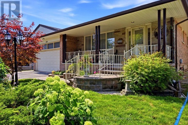 The front of the home with a wide covered porch, brick and stone exterior, and lush landscaping. - 394 Amstel Court, Oshawa