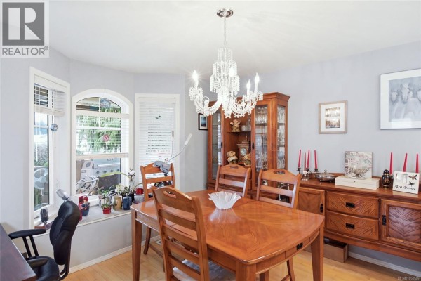 Dining room with wood table, hutch, buffet, and large bay window. - 3948 Valewood Dr, Nanaimo