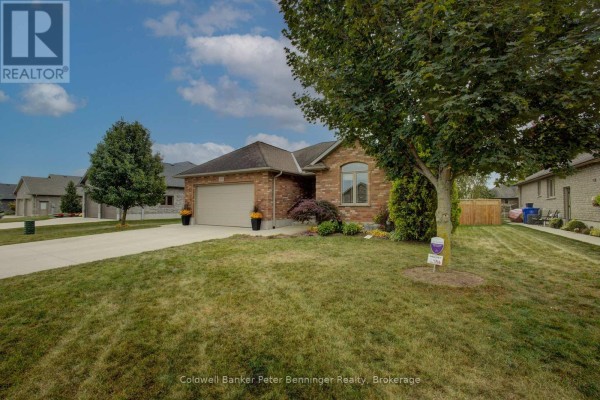 Side view of the brick bungalow showing the front yard and mature trees. - 395 3rd Street S, Hanover