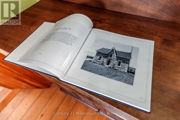 Open history book showing a black and white photo of the stone farmhouse. - 395 Elsinore Road N, South Bruce Peninsula