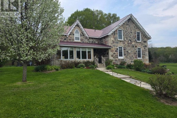 Stone farmhouse with a red roof, bay window addition, and a stone pathway. - 395 Elsinore Road N, South Bruce Peninsula