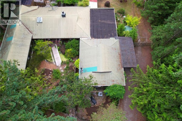 Overhead drone shot showing the unique architecture and rooflines of the property surrounded by trees. - 395 Lyngail Pl, Gabriola Island