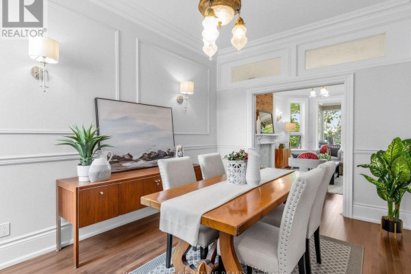 Living room with gold sofa, dark coffee table, and view into a dining room through an open doorway. - 395 Shaw Street, Toronto