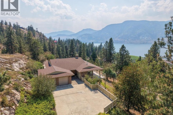 Aerial view of the ranch-style house with a long driveway and attached garage. - 3954 Valleyview Road, Penticton