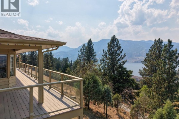 View from the deck of the house with trees and a distant lake. - 3954 Valleyview Road, Penticton