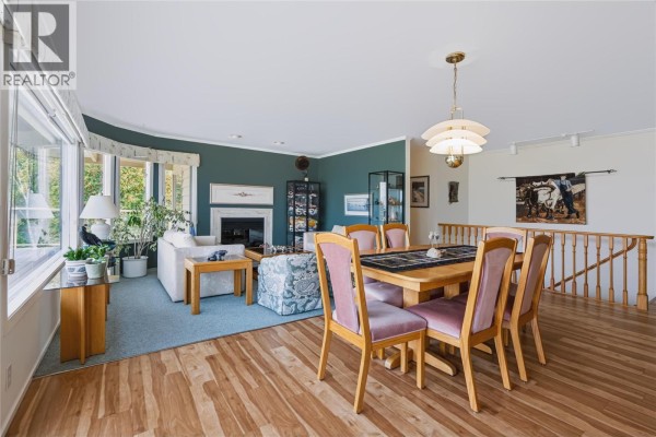 Dining area with a wooden table and upholstered chairs, adjacent to living space. - 3954 Valleyview Road, Penticton