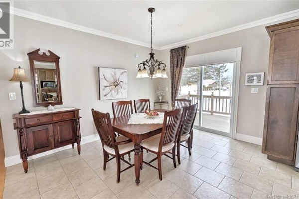 Dining area with a wooden table, six chairs, and sliding door to the deck. - 3956 Rue Luce, Tracadie