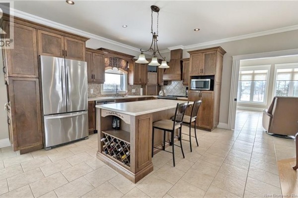 Kitchen with dark wood cabinets, stainless steel appliances, and an island with seating. - 3956 Rue Luce, Tracadie