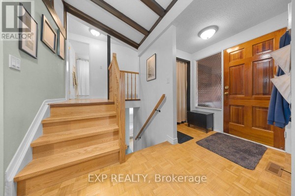 Interior entryway showing the front door and a staircase leading upstairs with wooden railings. - 396 Hatfield Crescent, Ottawa