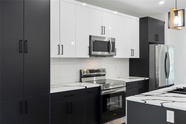 Close-up of modern kitchen cabinets, microwave, oven, and refrigerator. - 396 Union Avenue, Winnipeg