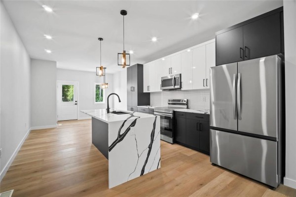 Kitchen island with sink and pendant lights, open to the living area. - 396 Union Avenue, Winnipeg