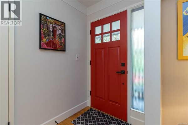 View of a white stucco house with a gray horizontal siding and a red door. - 3960 Cumberland Rd, Saanich