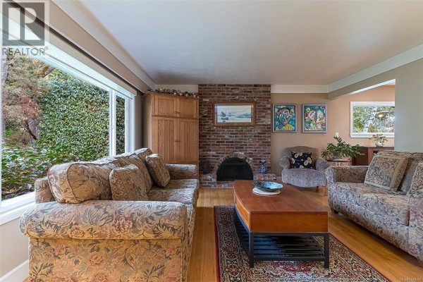 Exterior of a house at dusk with large windows showing warm interior lighting. - 3960 Cumberland Rd, Saanich