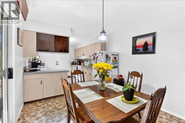 Kitchen with light wood cabinets, grey countertops, and a large window overlooking greenery. - 3962 Bruce St, Port Alberni